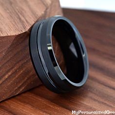 a black ring sitting on top of a wooden table next to a piece of wood