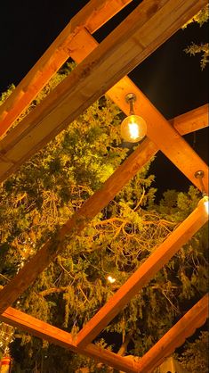 a wooden structure with lights hanging from it's sides and trees in the background