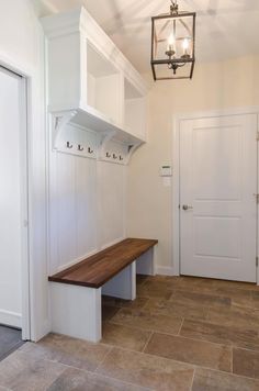 a room with a bench and some lights on the wall next to two white doors