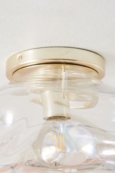 a close up of a light fixture on a white ceiling with a clear glass dome