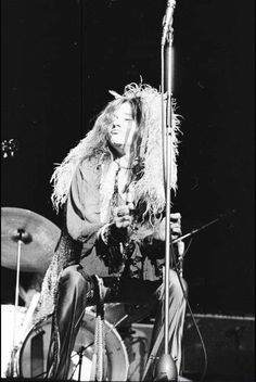 a man with long hair sitting in front of a microphone and playing the drums on stage