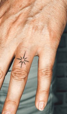 a person's hand with a small star tattoo on it