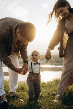 a man and woman holding hands with a small child in front of them on the grass