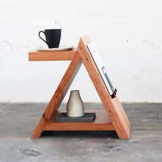 a wooden shelf with a coffee cup and book on it next to a white wall