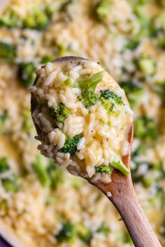 a spoon full of rice and broccoli with a wooden spoon in the bowl