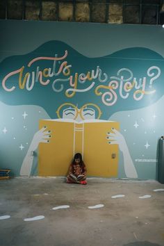 a woman sitting on the ground in front of a mural