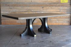 a wooden table sitting on top of a cement floor in front of a wood wall