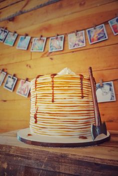 a cake sitting on top of a wooden table next to a string of pictures and a spatula