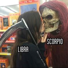 two women kissing each other in front of a fake skeleton head and the words libra scorpio on it