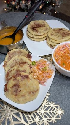 some food is sitting on a table next to a bowl of soup and two plates