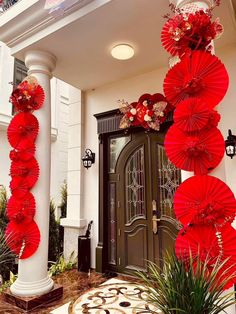 red paper umbrellas are hanging from the side of a building in front of a door