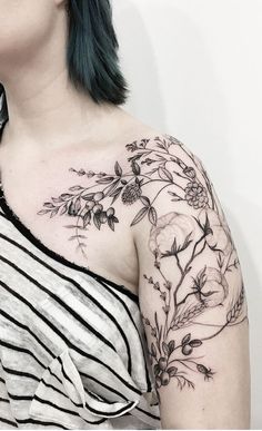 a woman with green hair wearing a black and white striped top has a flower tattoo on her left shoulder