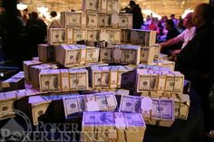 stacks of money sitting on top of each other in front of a table full of people