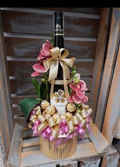 a bottle of wine sitting on top of a basket filled with flowers and other items