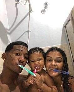 two adults and a child are brushing their teeth