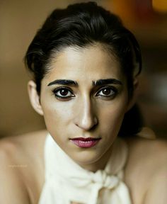 a woman with black hair and makeup is wearing a white bow tie, looking at the camera