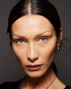 a woman with brown hair and blue eyes wearing a black top is looking at the camera