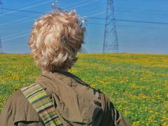 the back of a person's head in a field with power lines in the background