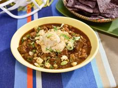 a bowl of chili with tortilla chips and sour cream in the middle on a table