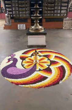 a clock that is sitting in the middle of a floor with flowers on top of it