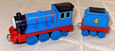 two toy trains sitting side by side on a white surface, one is blue and the other is red