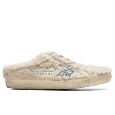 Italian footwear brand Golden Goose introduces its Women’s Super-Star Sabot. This comfortable yet elevated silhouette features a real dyed shearling upper along with a lace-up front. Along with a slip-on design, an embellished glitter star motif comprises the side panel along with gold foil branding stamped near it. Intentional markings and distressing are placed throughout, while the rubber outsole protects the silhouette’s overall durability. Dyed shearling upper Lace-up Slip-on Glitter star G Glitter Stars, Golden Goose, Slide Slipper, White Silver, Shoe Brands, Panel Siding, Wedding Sneaker, Sneaker Boots, Sale Items