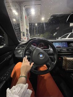 a person sitting in the driver's seat of a car with their hand on the steering wheel