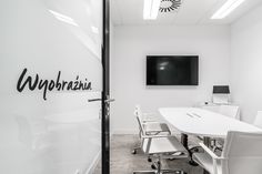 a conference room with white chairs and a flat screen tv mounted on the wall above it