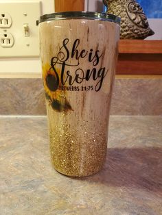 a tumbler cup with the words she is strong on it sitting on a counter