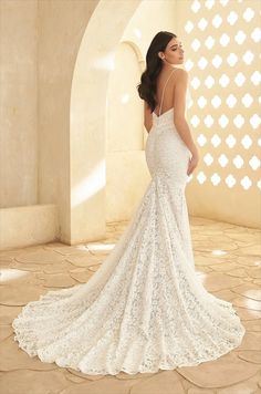 a woman in a white wedding dress standing on a tile floor with her back to the camera