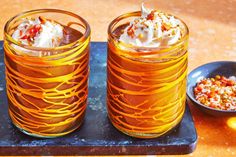 two glasses filled with ice cream sitting on top of a tray next to a bowl