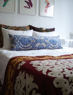 a bed with two paintings on the wall above it and pillows in front of it