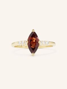 a yellow gold ring with an orange stone and two white diamonds on the band, set in