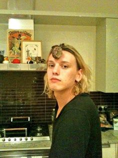 a woman standing in front of an oven with something on her head and looking at the camera