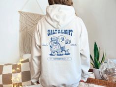 "Salt of the Earth, Light of the World is the mood in this cozy unisex hoodie, made with a heavy 50/50 cotton and polyester blend using 100% ethically grown US cotton. Order 1-3 sizes up for an extra relaxed, oversized fit. 🧂💡HOW TO ORDER💡🧂 1. Review all photos, including size charts and colors where available to determine best size  ✧ For oversized fit order 1-3 sizes up 2. Select Color 3. Select Size 4. Add personalization if available 5. Click \"Add to Cart\" 🫧WASHING INSTRUCTIONS🫧 Wash Relaxed Fit Long Sleeve Hoodie, Christian Gift Shop, Christian Streetwear, Salt Of The Earth, Salt And Light, Gift Shops, Light Of The World, Fashion Group, Color Charts