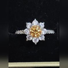 an orange diamond ring sitting on top of a black velvet box with white diamonds around it