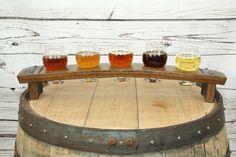 four glasses of beer sit on top of a barrel