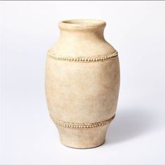 a white vase with beaded trim around the bottom and sides, on a white background