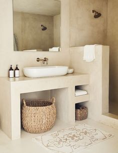 a bathroom with a sink, mirror and basket on the floor in front of it