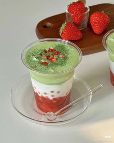 two desserts with strawberries on the top and green cream in the middle are sitting on a plate