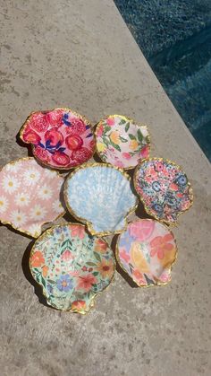 six colorful plates sitting next to a swimming pool