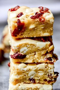 four bars stacked on top of each other with cranberries and almonds in the middle