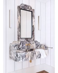 a marble sink in a white bathroom with wood flooring and wall mounted mirror above it