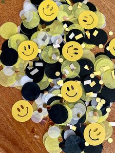 a bunch of yellow and black smiley faces on a wooden table with white circles around them