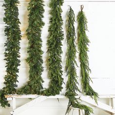 some green plants hanging from the side of a white wall next to a chair and table