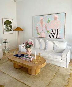 a living room filled with furniture and a painting on the wall above it's coffee table