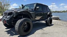 a black jeep is parked near the water