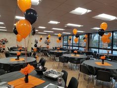 tables with black and orange tablecloths, silverware and balloons in an office setting