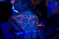 a woman with a world map tattoo on her arm and chest, in the dark