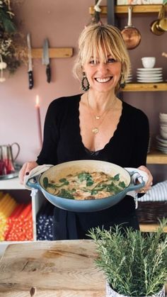 a woman holding a bowl of soup in her hands